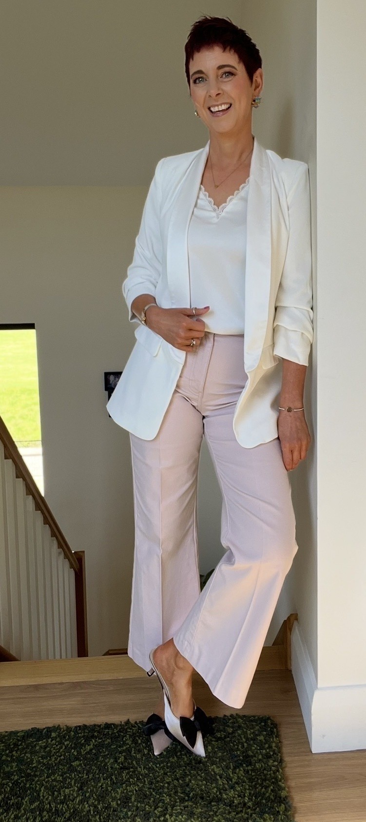Deirdre Treanor on stairs in a white blazer and pink trousers